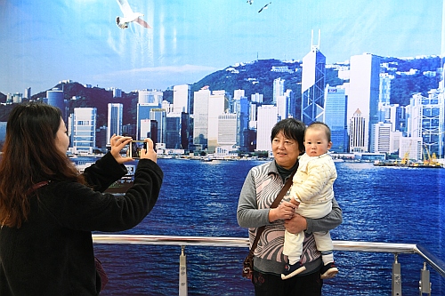 圖示參觀者於一幅以維多利亞港爲主題的３Ｄ畫前留影。畫中的維多利亞港內穿梭不絕的船舶，連同鱗次櫛比的摩天大樓，拼凑出一個別具風貌的動人景致。