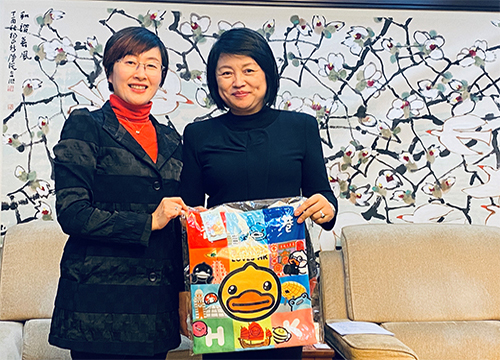 駐滬辦主任蔡亮（左）與中共上海市委宣傳部副部長胡佩豔（右）於會後合照，並展示駐滬辦首次與香港品牌B.Duck小黃鴨跨界合作，以香港美食和旅遊為主題製作的八款獨家紀念品之一——帆布袋