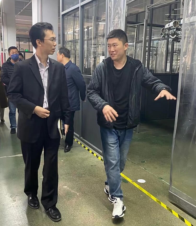 安徽威妮達服飾有限公司董事長助理冉海川（右一）向駐滬辦經貿關係總監馬明亮（左一）介紹產品生產線。