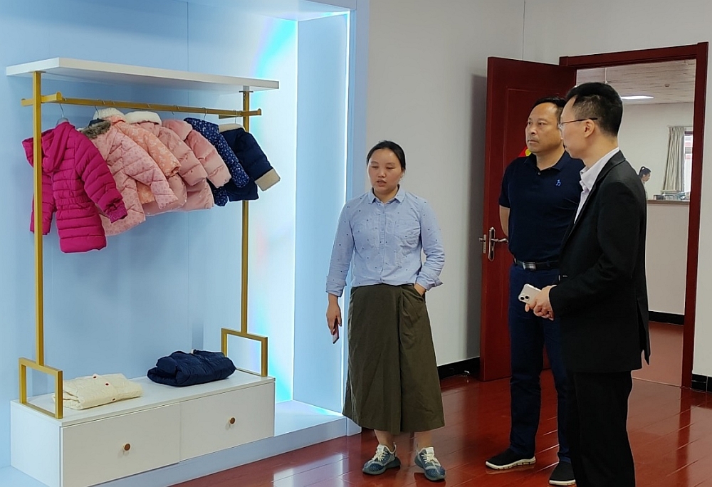 六安市委外事辦專職副主任秦飛(中)陪同駐滬辦經貿關係總監馬明亮(右)考察一家服裝公司